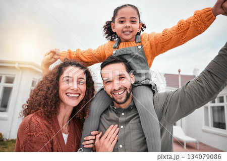 Family portrait, piggy back and happy man, woman and child in yard of new house, happiness and security at home. Interracial mother, father and girl bonding in backyard together with love and smile. 134079086