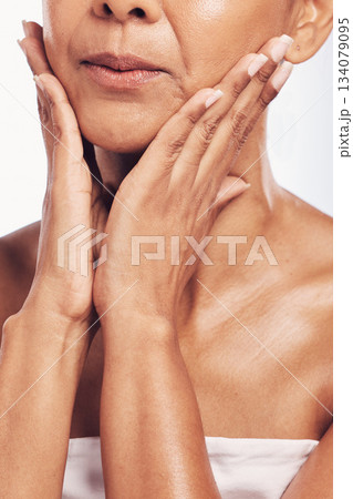 Hands, mouth and beauty with a mature woman in studio for skincare, anti aging treatment or cosmetics. Skin, facial and wellness with a senior female touching her face for hydration closeup 134079095
