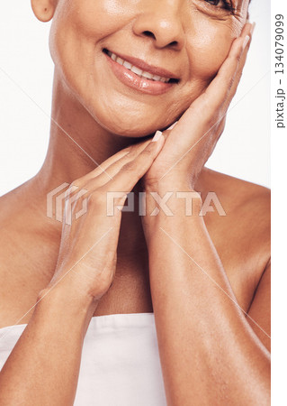 Hands, mouth and beauty with a senior woman in studio for skincare, anti aging treatment or cosmetics. Skin, facial and wellness with a mature female touching her soft face for hydration closeup 134079099