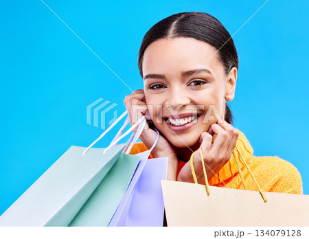 Shopping bags, studio and woman portrait with a smile and happiness from boutique sale. Happy, customer and female model with store bag and sales choice in isolated blue background with young person 134079128