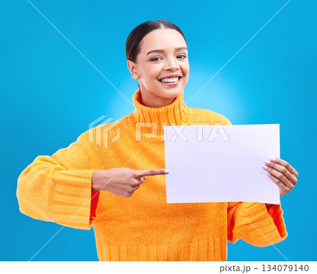 Poster, point and portrait of woman on blue background for announcement, news and information. Advertising, mockup studio and isolated happy girl with paper sign for brand, logo and product placement Poster, point and portrait of woman on blue background for announcement, news and information. Advertising, mockup studio and isolated happy girl with paper sign for brand, logo and product placement 134079140
