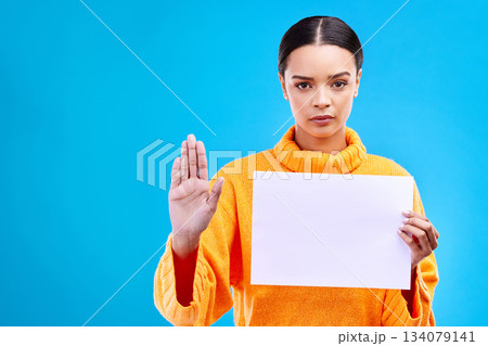 Serious, stop and woman with a poster in a studio with mockup, copy space and blank space. Confidence, portrait and female model from Brazil with a paper and hand gesture isolated by blue background. 134079141