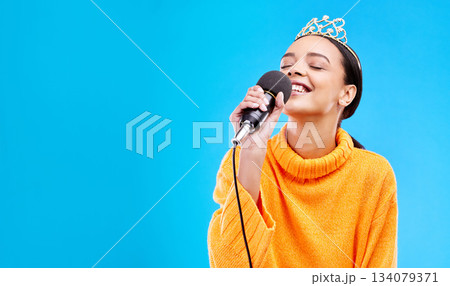 Singer woman, crown and microphone in studio mockup with smile for singing performance by blue background. Happy gen z girl, model or recording artist mic for karaoke, music and mock up with tiara Singer woman, crown and microphone in studio mockup with smile for singing performance by blue background. Happy gen z girl, model or recording artist mic for karaoke, music and mock up with tiara 134079371