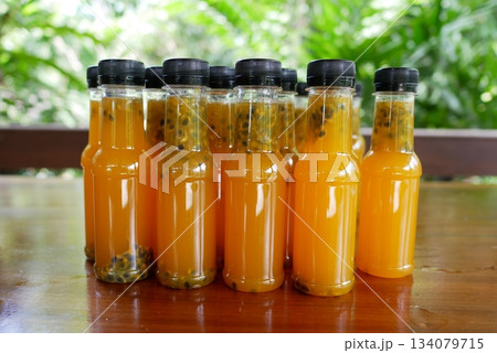 Passion fruit juice in bottles on wooden table with nature background. 134079715