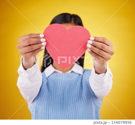 Cover, paper and heart with woman in studio for love, support and romance. Valentines day, kindness and date with female hiding with symbol on yellow background for health, happiness and hope mockup Cover, paper and heart with woman in studio for love, support and romance. Valentines day, kindness and date with female hiding with symbol on yellow background for health, happiness and hope mockup 134079956