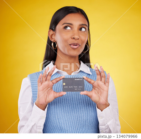 Credit card, thinking and Indian woman on yellow background for bank, investment and payment in studio. Banking mockup, finance and happy girl with plastic for budget, commerce and discount purchase 134079966