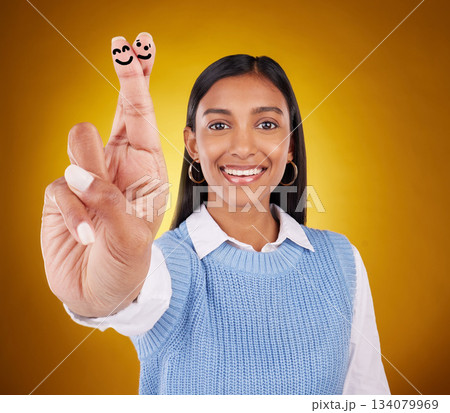 Smiley face, fingers crossed and portrait of Indian woman in studio with drawing for hand sign, symbol and luck. Emoji mockup, yellow background and happy girl smile for wish, hope and lucky gesture Smiley face, fingers crossed and portrait of Indian woman in studio with drawing for hand sign, symbol and luck. Emoji mockup, yellow background and happy girl smile for wish, hope and lucky gesture 134079969