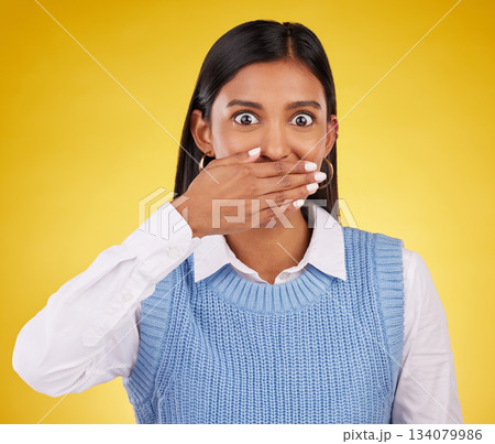 Portrait, wow and gossip with a woman on a yellow background in studio looking surprised by an announcement. Face, shock and news with an attractive young female standing hand over mouth in awe Portrait, wow and gossip with a woman on a yellow background in studio looking surprised by an announcement. Face, shock and news with an attractive young female standing hand over mouth in awe 134079986
