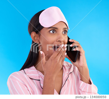 Phone call, surprise and female in pyjamas in studio with shocking, winning or good news. Communication, shock and woman model having gossip conversation with wtf, omg or wow face by blue background. Phone call, surprise and female in pyjamas in studio with shocking, winning or good news. Communication, shock and woman model having gossip conversation with wtf, omg or wow face by blue background. 134080050