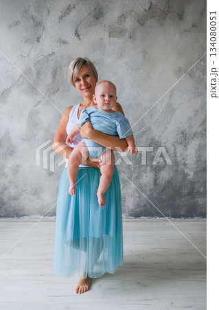 Moscow, Russia, 29.06.23. A woman is holding a baby in a blue shirt Moscow, Russia, 29.06.23. A woman is holding a baby in a blue shirt 134080051
