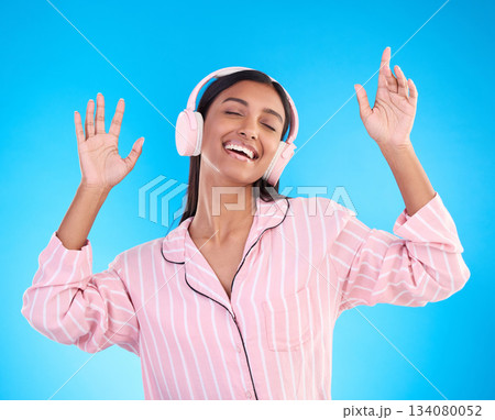 Smile, dance and woman in pajamas, headphones and inspiration against a blue studio background. Female, happy and lady with headset, waking up and dancing for motivation, wellness and streaming music Smile, dance and woman in pajamas, headphones and inspiration against a blue studio background. Female, happy and lady with headset, waking up and dancing for motivation, wellness and streaming music 134080052