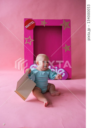 Moscow, Russia, 29.06.23. A baby is sitting in front of a Barbie doll box 134080053