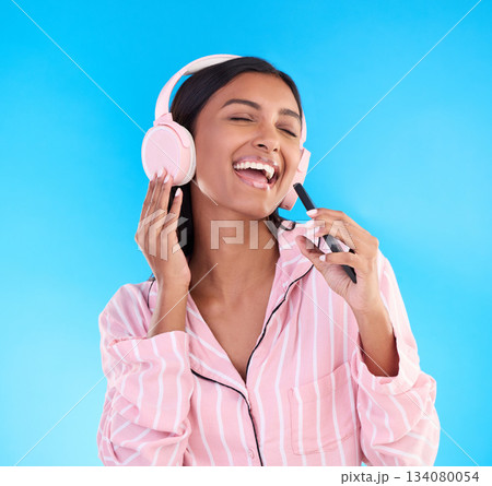 Singing, music and a woman with phone before bedtime isolated on a blue background in a studio. Happy, karaoke and a girl listening to the radio, app audio or streaming songs in pyjamas on a mobile Singing, music and a woman with phone before bedtime isolated on a blue background in a studio. Happy, karaoke and a girl listening to the radio, app audio or streaming songs in pyjamas on a mobile 134080054
