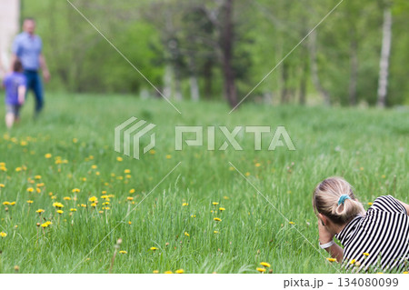 khabarovsk, russia, 06.07.2013. A woman is laying in the grass, looking at something khabarovsk, russia, 06.07.2013. A woman is laying in the grass, looking at something 134080099