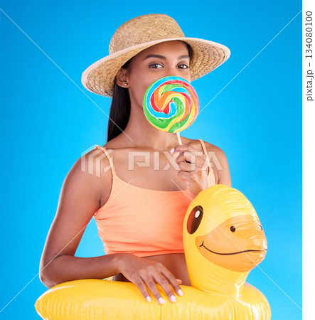 Portrait, lollipop and rubber duck with a woman on a blue background in studio ready for summer swimming. Happy, travel and vacation with an attractive young female looking excited to relax or swim Portrait, lollipop and rubber duck with a woman on a blue background in studio ready for summer swimming. Happy, travel and vacation with an attractive young female looking excited to relax or swim 134080100