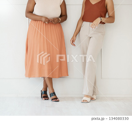 Fashion, formal and business woman friends at office against a wall in team conversation or chat. Discussion, planning and legs of professional corporate employee women in luxury outfits at workplace Fashion, formal and business woman friends at office against a wall in team conversation or chat. Discussion, planning and legs of professional corporate employee women in luxury outfits at workplace 134080330