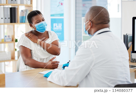 Doctor, covid and patient with shoulder pain in hospital, fibromyalgia or inflammation. Face mask, healthcare professional and black woman with injury, arthritis or painful tendinitis in consultation 134080377