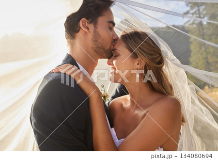Couple, wedding and forehead kiss with vail for love, compassion or affection together in nature. Marred man kissing woman on head and hugging in marriage, relationship or loving embrace outdoors Couple, wedding and forehead kiss with vail for love, compassion or affection together in nature. Marred man kissing woman on head and hugging in marriage, relationship or loving embrace outdoors 134080694
