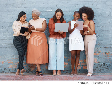 Happy, talking and women on a brick wall with tech for communication, social network and advice. Team, diversity and group of female employees speaking while using technology in the city for work 134081644