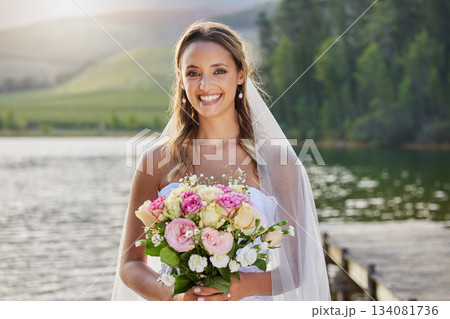 Portrait, happy bride and bouquet at lake, nature and celebration of commitment, union and marriage. Woman, smile and outdoor wedding of flowers, bridal fashion and excited to celebrate beautiful day 134081736
