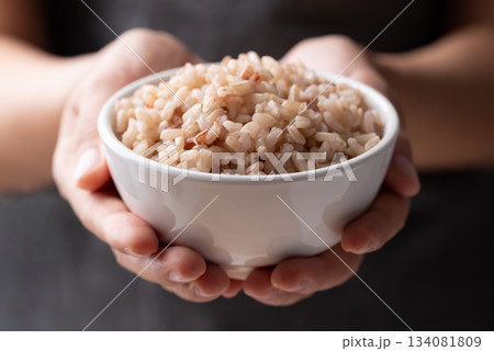 Cooked Thai brown rice in a bowl holding by hand, Healthy eating 134081809