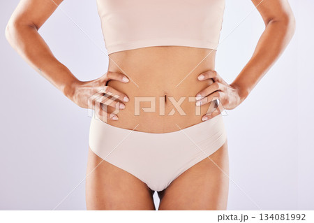 Healthy lifestyle, body and stomach of woman in studio as motivation for weight loss, diet or fitness. Healthy female model on a white background with hands on waist for health, wellness or underwear Healthy lifestyle, body and stomach of woman in studio as motivation for weight loss, diet or fitness. Healthy female model on a white background with hands on waist for health, wellness or underwear 134081992