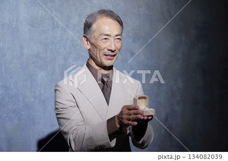 指輪を渡すスーツを着たシニア男性　黒背景 134082039