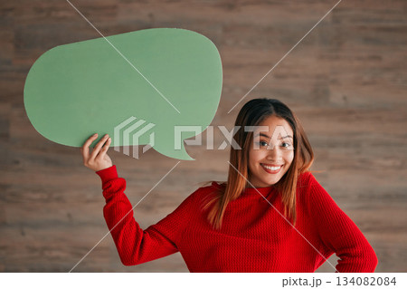 Business woman, speech bubble and portrait by wall with happiness, opinion and social media in workplace. Businesswoman, paper and poster for news, announcement and happy with sign, vote and voice 134082084