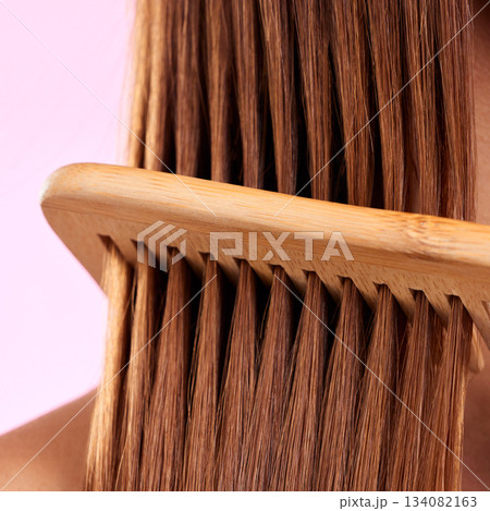 Beauty, comb and wood with hair of woman for health, salon and close up in studio. Wellness, keratin and natural bamboo brush with female model for cosmetics, self care and shine on pink background Beauty, comb and wood with hair of woman for health, salon and close up in studio. Wellness, keratin and natural bamboo brush with female model for cosmetics, self care and shine on pink background 134082163