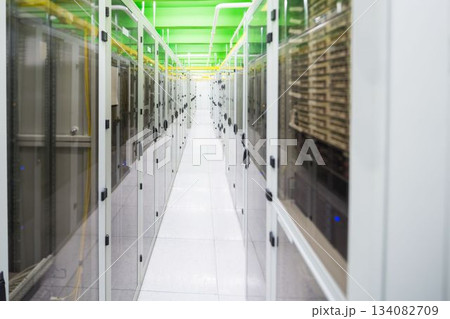 Flat-design corridor featuring white server racks, glass doors, overhead green trays with cables Flat-design corridor featuring white server racks, glass doors, overhead green trays with cables 134082709