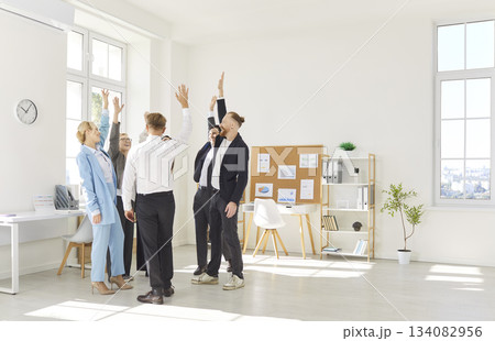 Professional Business Team Celebrating Success With Raised Hands In Office 134082956