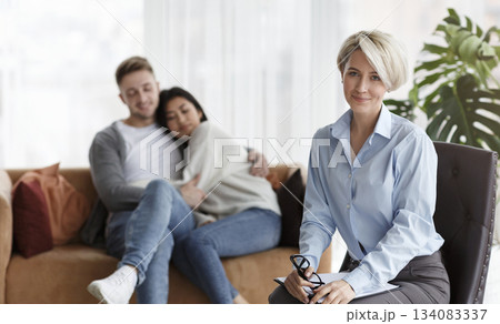 Effective Psychotherapy. Happy Psychologist Sitting Next To Loving Spouses After Successful Reconciliation In Office. Selective Focus 134083337