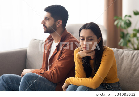 Marital Crisis. Unhappy Arabic Couple Sitting On Couch At Home, Having Relationship Problems. Bad Marriage, Breakup Concept. Selective Focus On Frustrated Woman 134083612