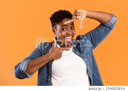 Capture The Moment. Smiling Black Plus-Size Lady Framing Face With Fingers Posing Looking At Camera On Yellow Background. Studio Shot. Frame Your Beauty Concept. Capture The Moment. Smiling Black Plus-Size Lady Framing Face With Fingers Posing Looking At Camera On Yellow Background. Studio Shot. Frame Your Beauty Concept. 134083614