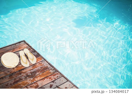 Hat and flip-flop on pier by swimming pool Hat and flip-flop on pier by swimming pool 134084017