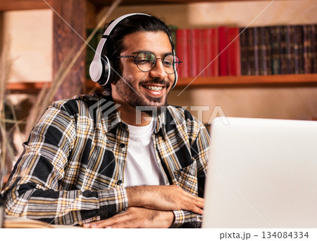 Happy Indian Student Guy Having Online Lecture Via Video Call Sitting At Laptop In Library Indoors. E-Learning And Virtual Classes. Modern Distance Study Concept. Selective Focus Happy Indian Student Guy Having Online Lecture Via Video Call Sitting At Laptop In Library Indoors. E-Learning And Virtual Classes. Modern Distance Study Concept. Selective Focus 134084334