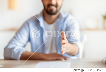 Partnership Concept. Friendly Young Businessman Giving Hand For Handshake At Camera, Positive HR Manager Greeting Somebody And Offering Cooperation In Office, Cropped Image With Selective Focus Partnership Concept. Friendly Young Businessman Giving Hand For Handshake At Camera, Positive HR Manager Greeting Somebody And Offering Cooperation In Office, Cropped Image With Selective Focus 134084523