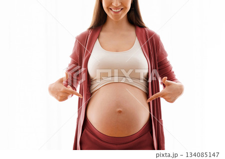 Happy Pregnancy. Positive Young Woman Pointing At Her Naked Pregnant Belly With Two Hands, Standing Against Window At Home, Cheerful Expectant Mother Enjoying Prenatal Time, Copy Space 134085147