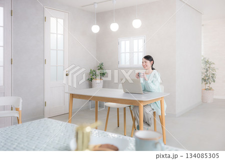 パソコンを使いながらコーヒーを飲む女性　広角の全身 134085305