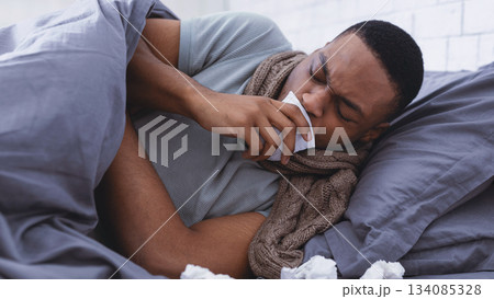 Pneumonia. Sick African American Man Coughing Holding Paper Napkin Near Mouth Suffering From Coronavirus Disease Lying In Bed At Home. Covid-19 And Inflamed Lungs Symptoms Concept Pneumonia. Sick African American Man Coughing Holding Paper Napkin Near Mouth Suffering From Coronavirus Disease Lying In Bed At Home. Covid-19 And Inflamed Lungs Symptoms Concept 134085328