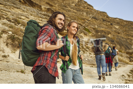Man tourist and young girl hiking in nature with a group of tourists in mountains. Man tourist and young girl hiking in nature with a group of tourists in mountains. 134086041