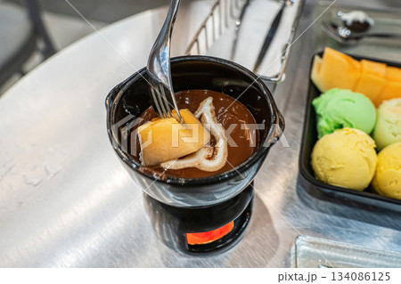 Dipping melon in chocolate fondue 134086125