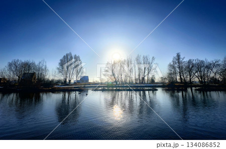 A Tranquil River Scene with Bright Sunlight and a Mirrored Reflection on the Water A Tranquil River Scene with Bright Sunlight and a Mirrored Reflection on the Water 134086852