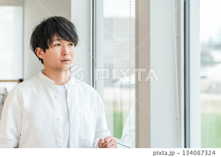 マイホームのリビングで窓の外の景色を眺める若いアジア人男性 134087324