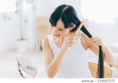 ヘアアイロンを使う若い女性 134087372
