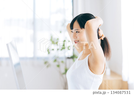 歯ブラシを咥えたまま髪の毛をまとめる若い女性 134087531