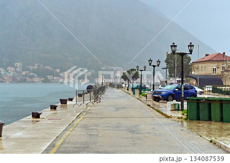Wet Embankment in a Coastal Town on a Foggy Overcast Day with a View of Mountains and Old Houses Wet Embankment in a Coastal Town on a Foggy Overcast Day with a View of Mountains and Old Houses 134087539