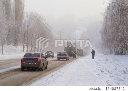 Snow-Covered Slippery City Road and Truck in Snowfall and Poor Visibility Conditions 134087542