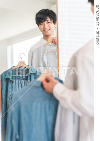 鏡を見ながら服をコーディネートする若いアジア人男性 鏡を見ながら服をコーディネートする若いアジア人男性 134087630