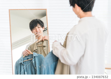 鏡を見ながら服をコーディネートする若いアジア人男性 134087632